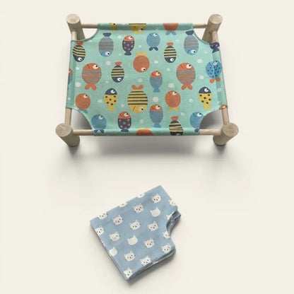 Hamac chat sur pied avec toile décorée de têtes de chats et support en bois pour un couchage surélevé.