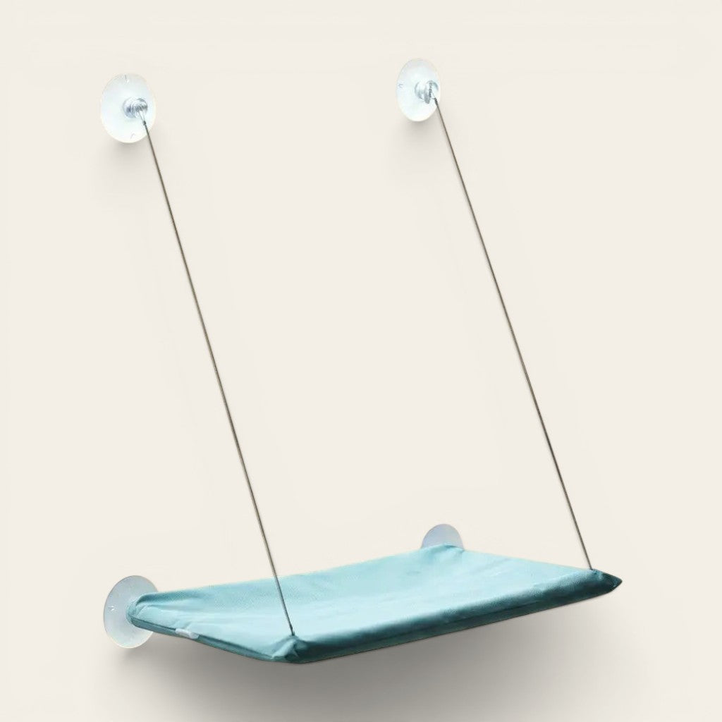 Hamac ventouse chat bleu fixé à la fenêtre grâce à des ventouses résistantes pour un repos en hauteur sécurisé.