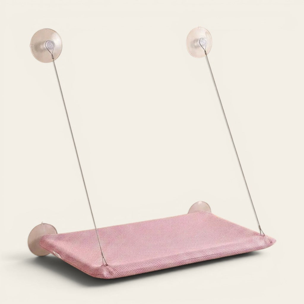 Hamac ventouse chat rose en tissu respirant installé sur une vitre pour créer un couchage suspendu confortable.
